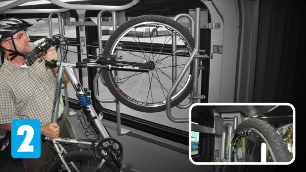 Cyclist installing bicycle into interior bus bike rack