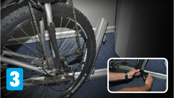 Rear tire of bicycle shown in the wheel rack with an inset of the cyclist buckling the rear wheel into the rack.